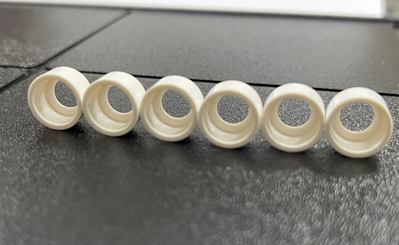 A row of white plastic tubes with holes in them are sitting on a table.