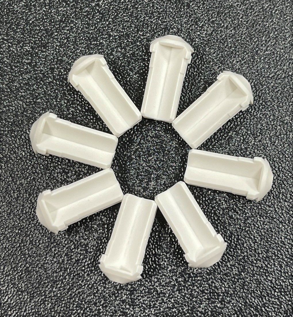 A group of white plastic tubes are sitting in a circle on a gray surface.