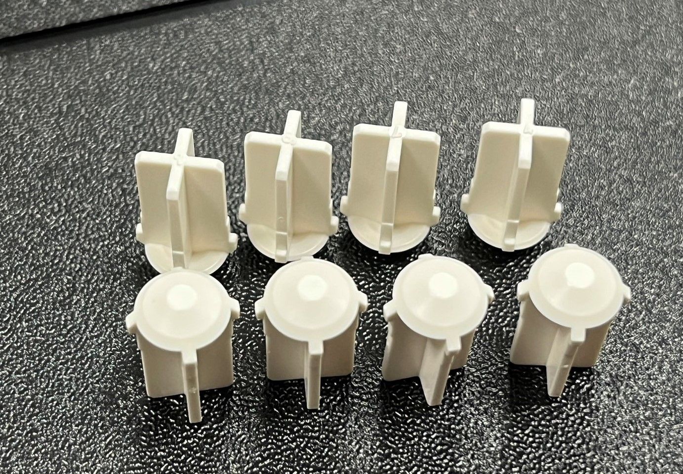 A group of white plastic pieces are sitting on a black surface.