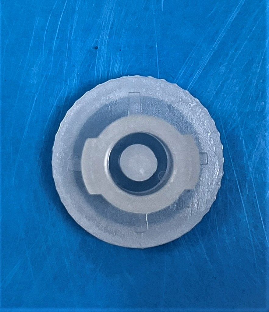A clear plastic circle with a hole in the middle on a blue surface.