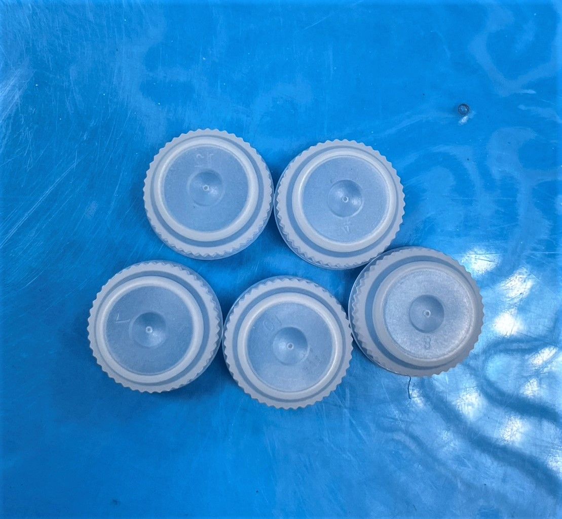 A group of plastic bottle caps are sitting on a blue surface.