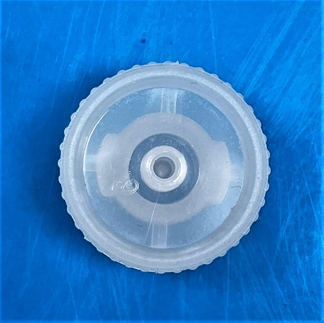 A clear plastic circle with a hole in the middle on a blue surface.