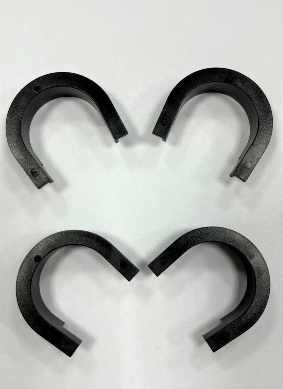 Four black horseshoes are sitting on a white surface in the shape of a heart.