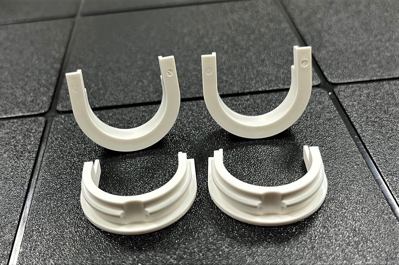 A pair of white plastic rings are sitting on a black tile floor.