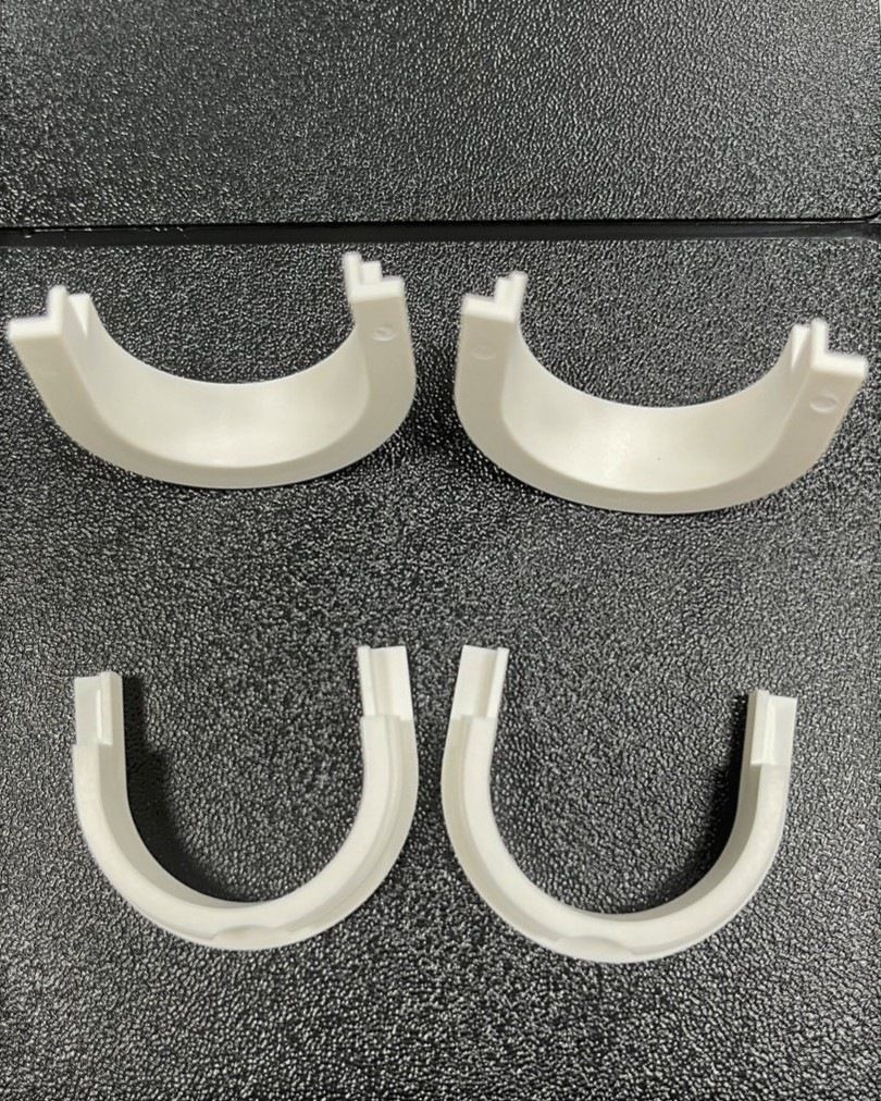 Three white plastic pieces are sitting on a black surface.