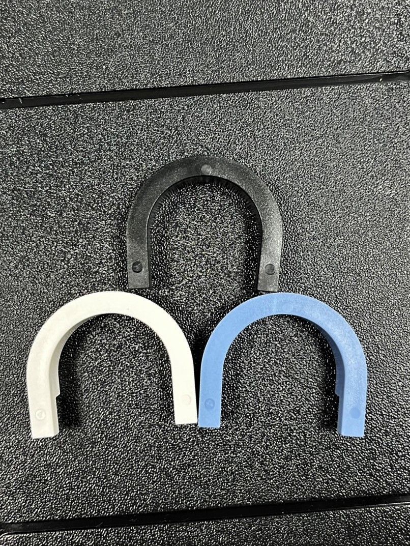 Two horseshoes are sitting on a gray surface.