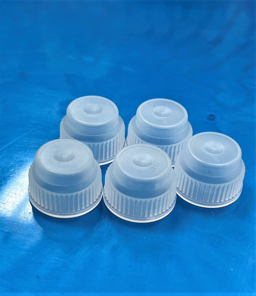 A group of plastic bottle caps are sitting on top of each other on a blue surface.
