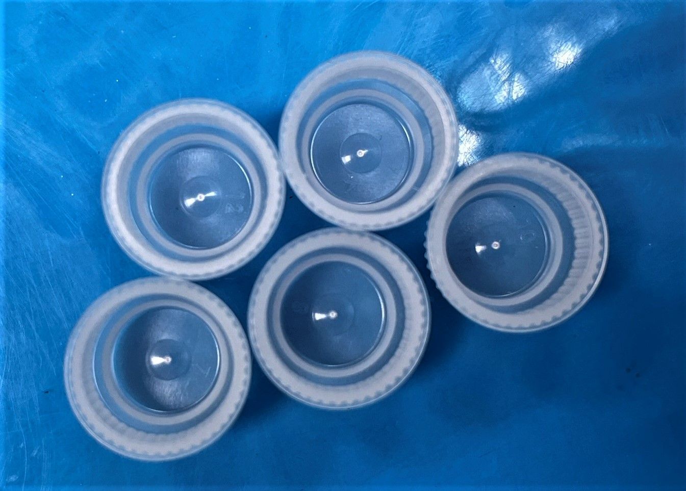 A group of plastic bottle caps are stacked on top of each other on a blue surface