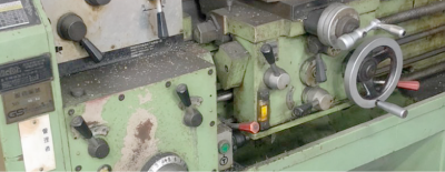 A close up of a lathe with a lot of controls on it.