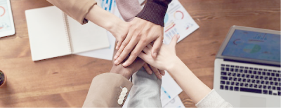 A group of people are putting their hands together on a table.