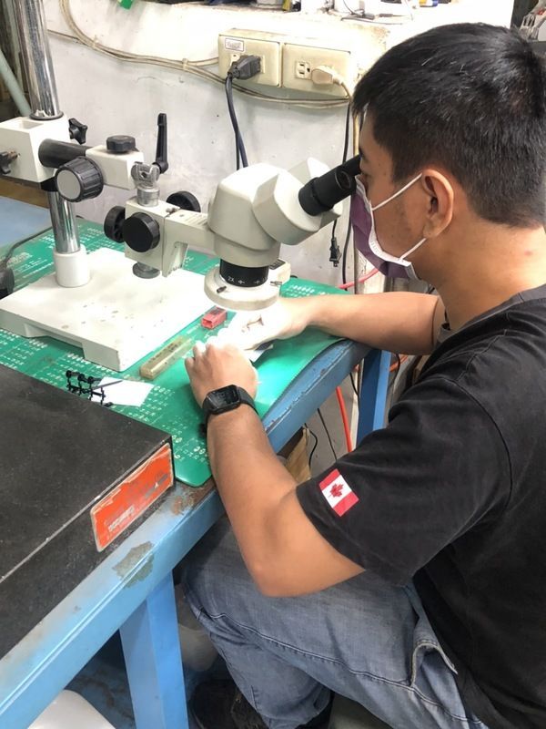 A man wearing a mask is looking through a microscope.