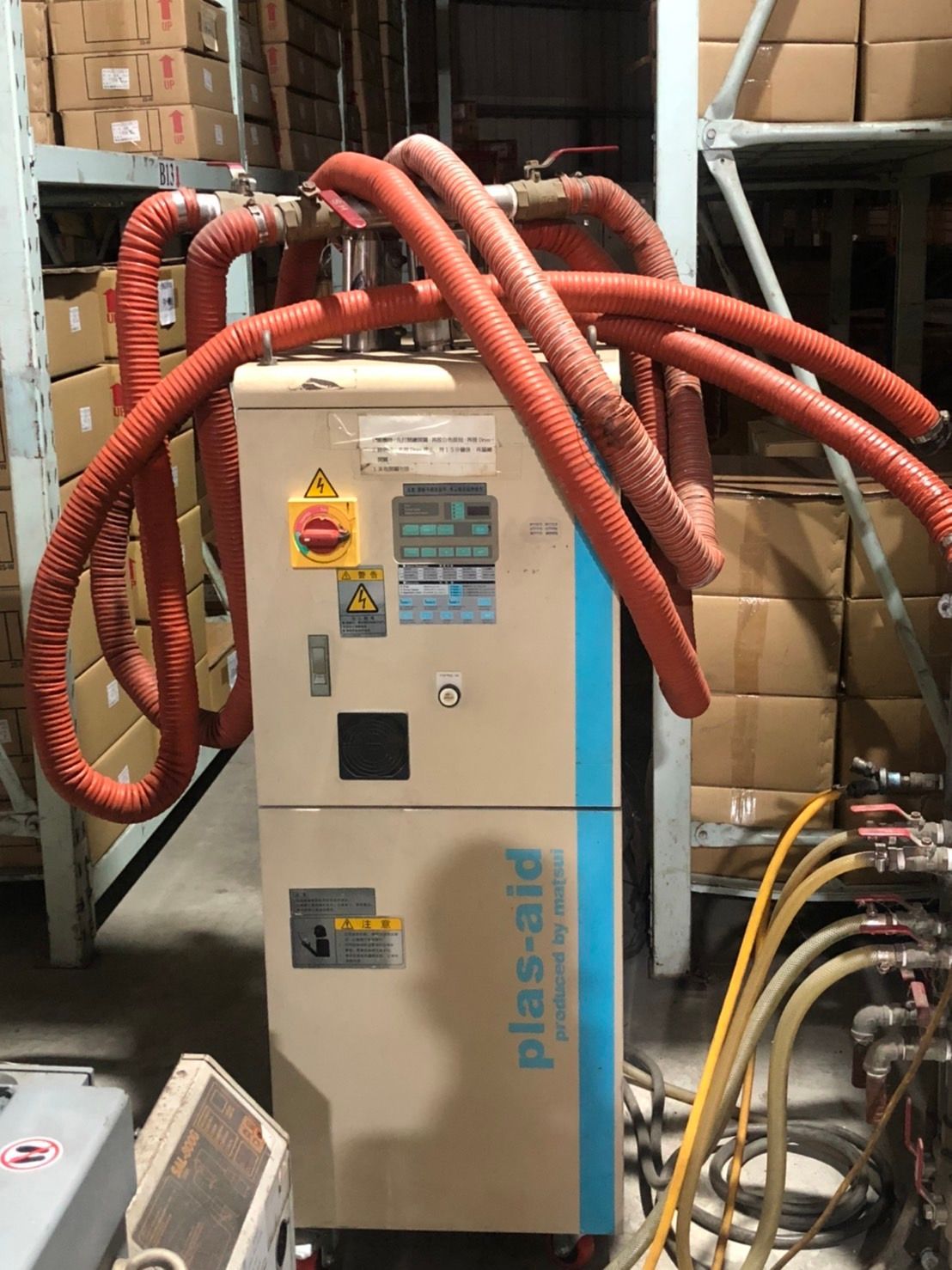 A machine with red hoses attached to it is in a warehouse.