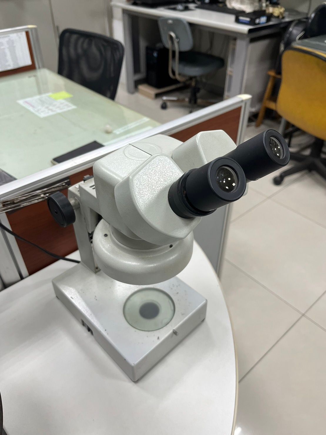 A microscope is sitting on a table in an office.