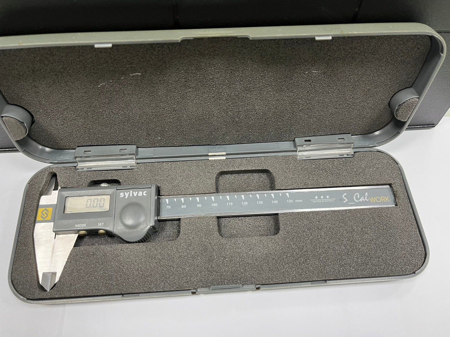 A digital caliper is sitting in a foam case