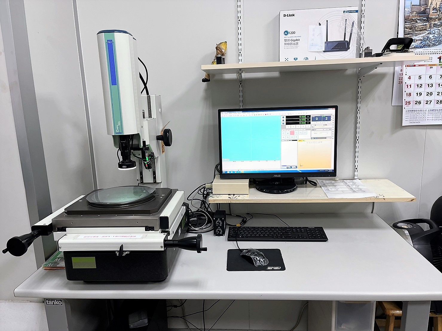 A desk with a computer and a microscope on it.