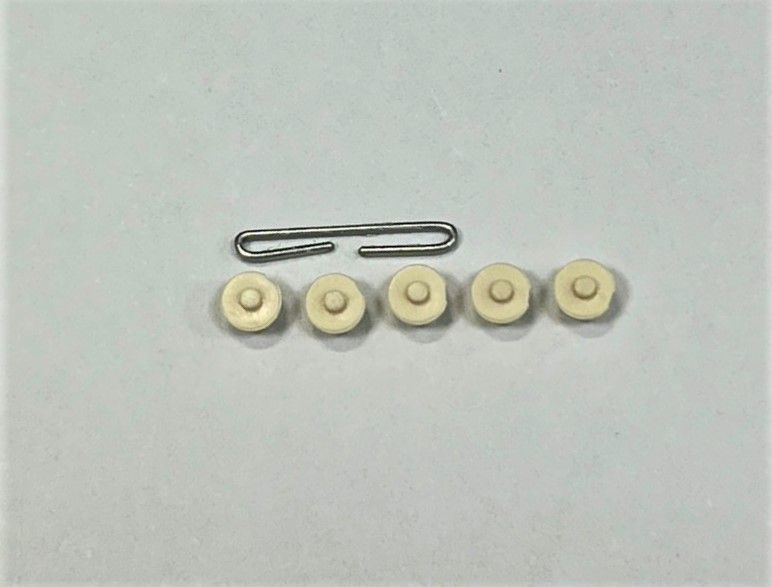 A paper clip is next to a group of buttons on a white surface.