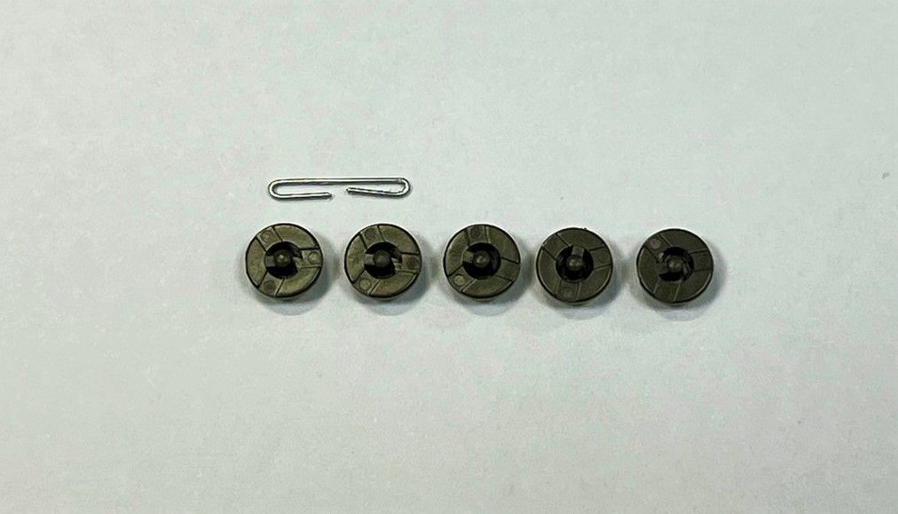 A group of buttons and a clip are sitting on a white surface.
