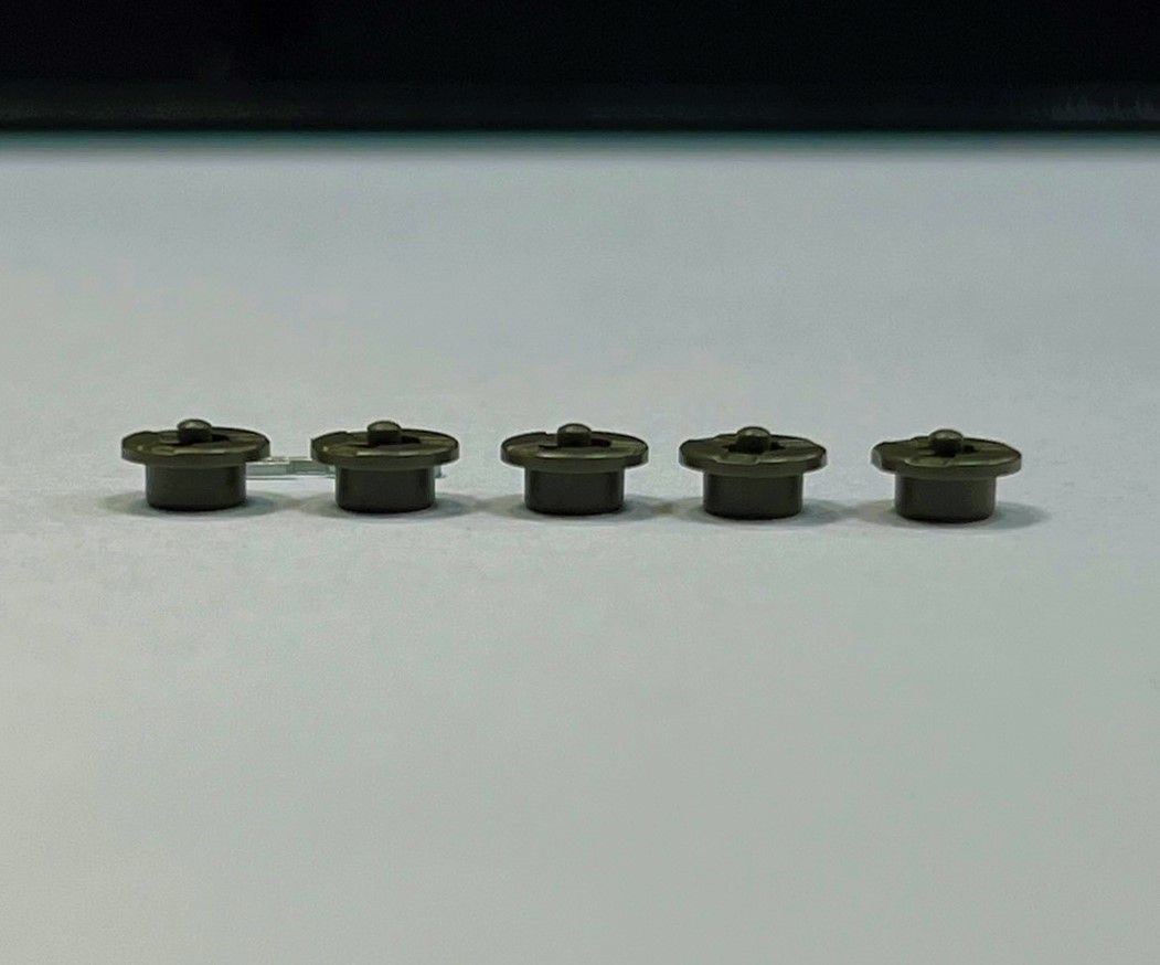 A row of small metal objects are lined up on a white surface.