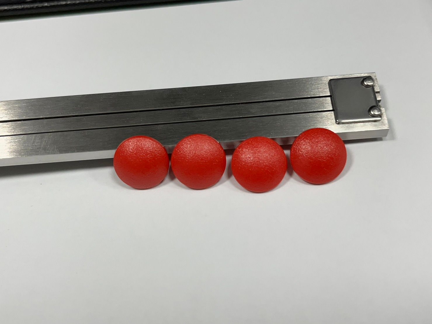 Three red balls are sitting next to each other on a white surface.