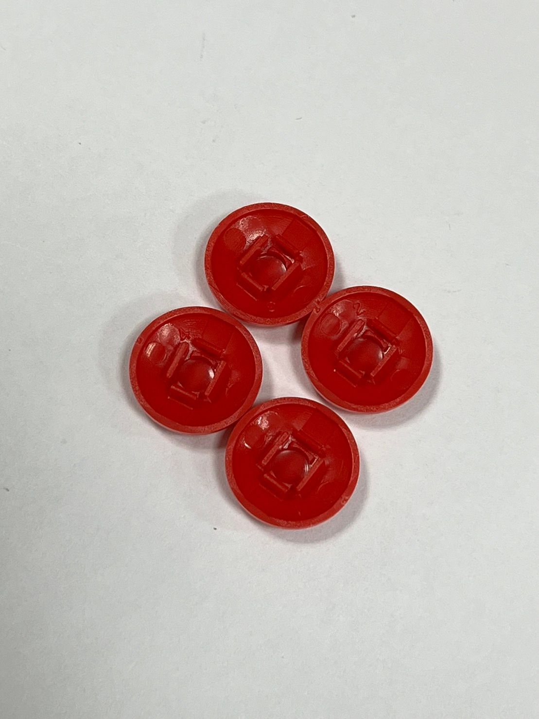Four red buttons are sitting on top of each other on a white surface.