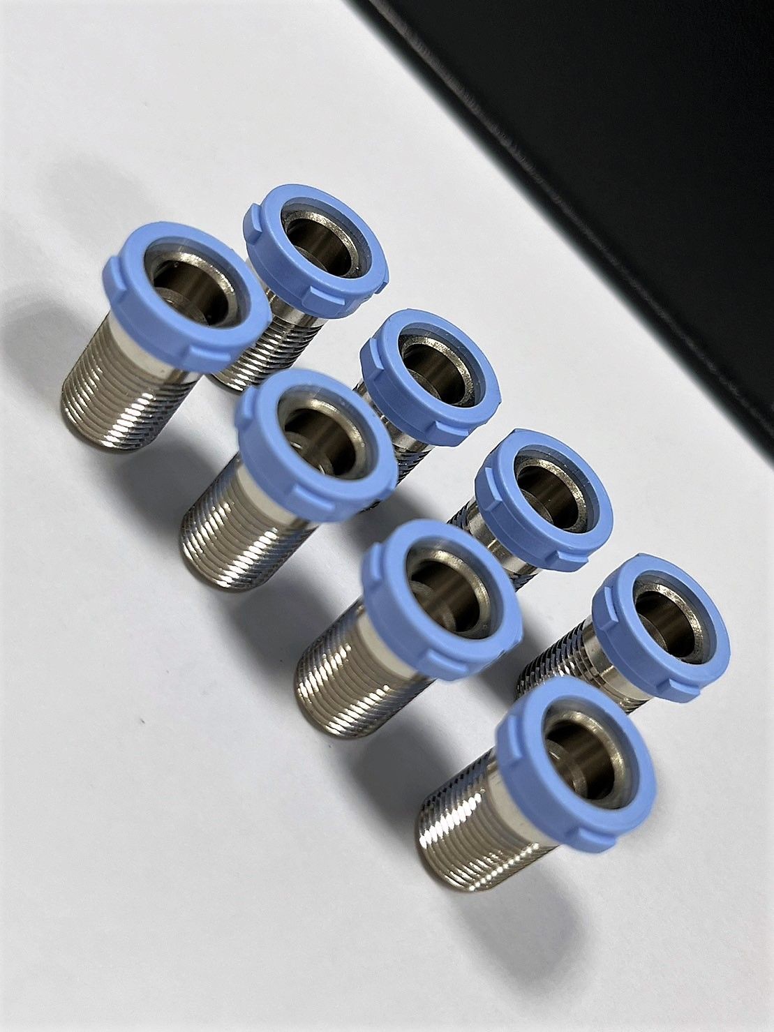 A close up of a row of screws with blue caps on a table.