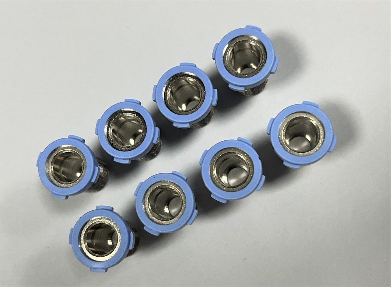 A row of blue and silver connectors are lined up on a white surface