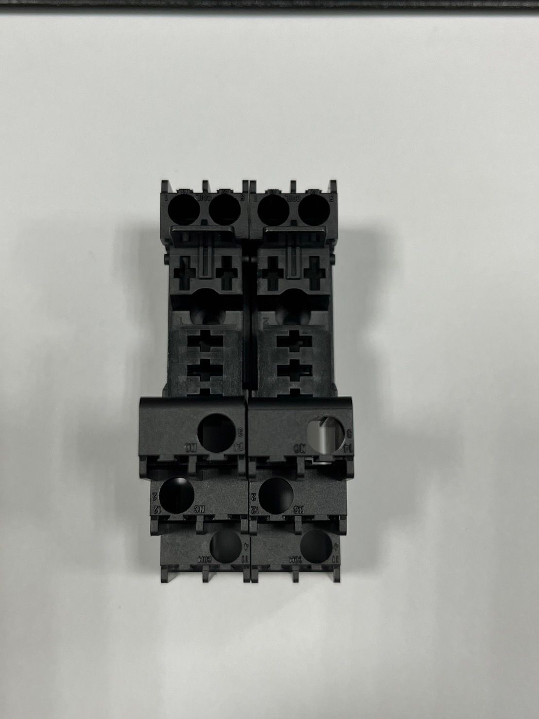 A close up of a black electrical connector on a white surface.
