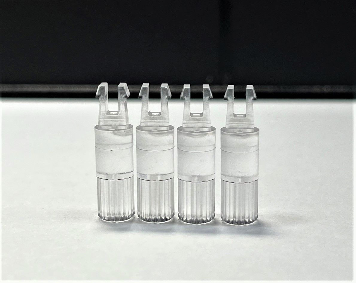 Four clear plastic tubes are lined up on a white surface.
