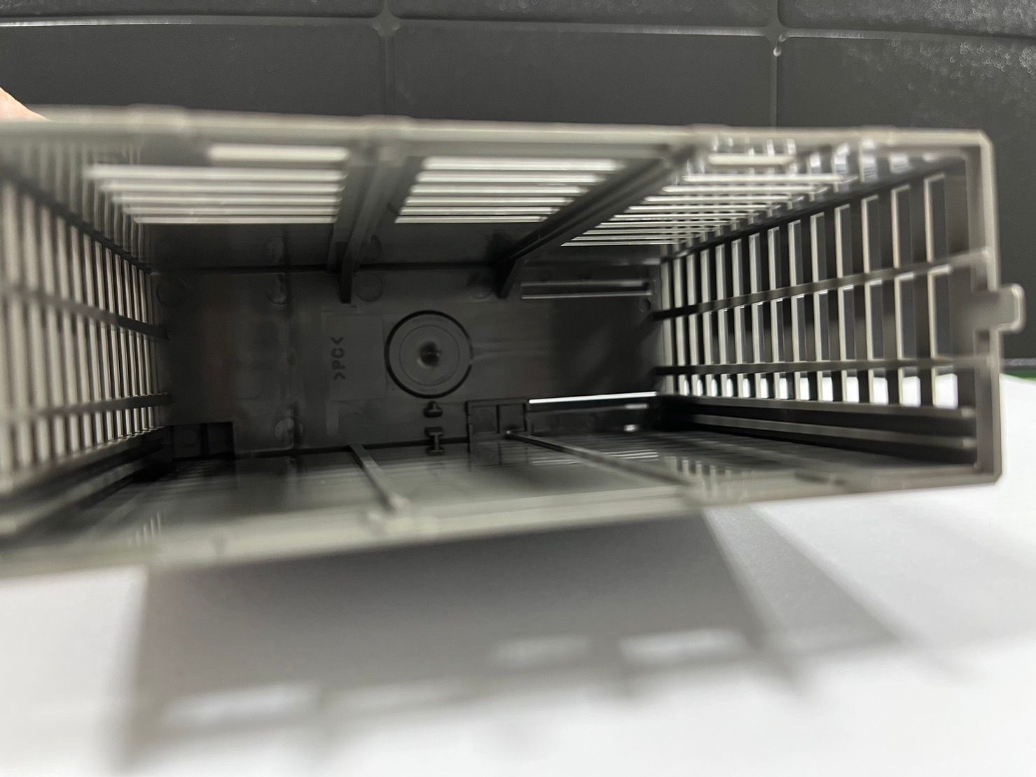 A close up of a plastic cage on a white surface.