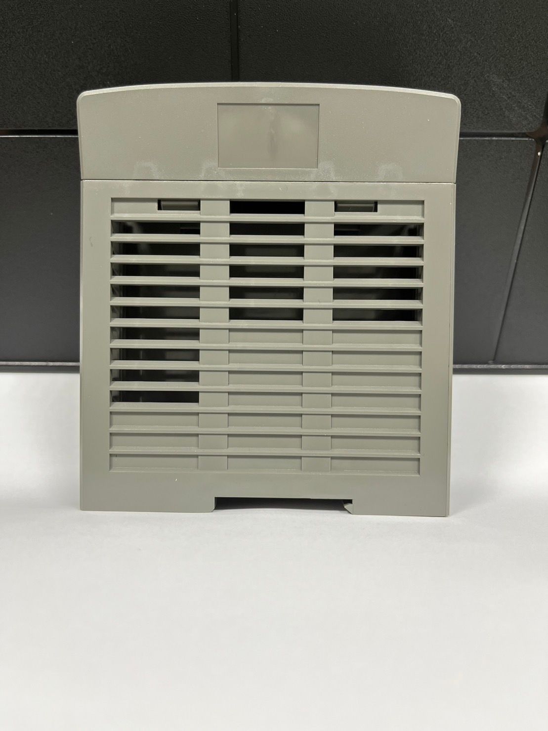 A gray plastic item is sitting on a white surface.