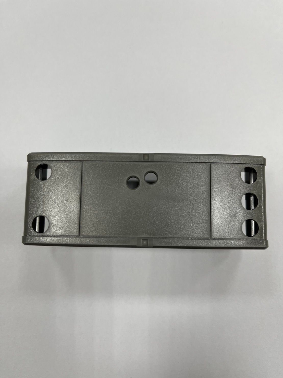 A gray plastic box with holes in it is sitting on a white surface.