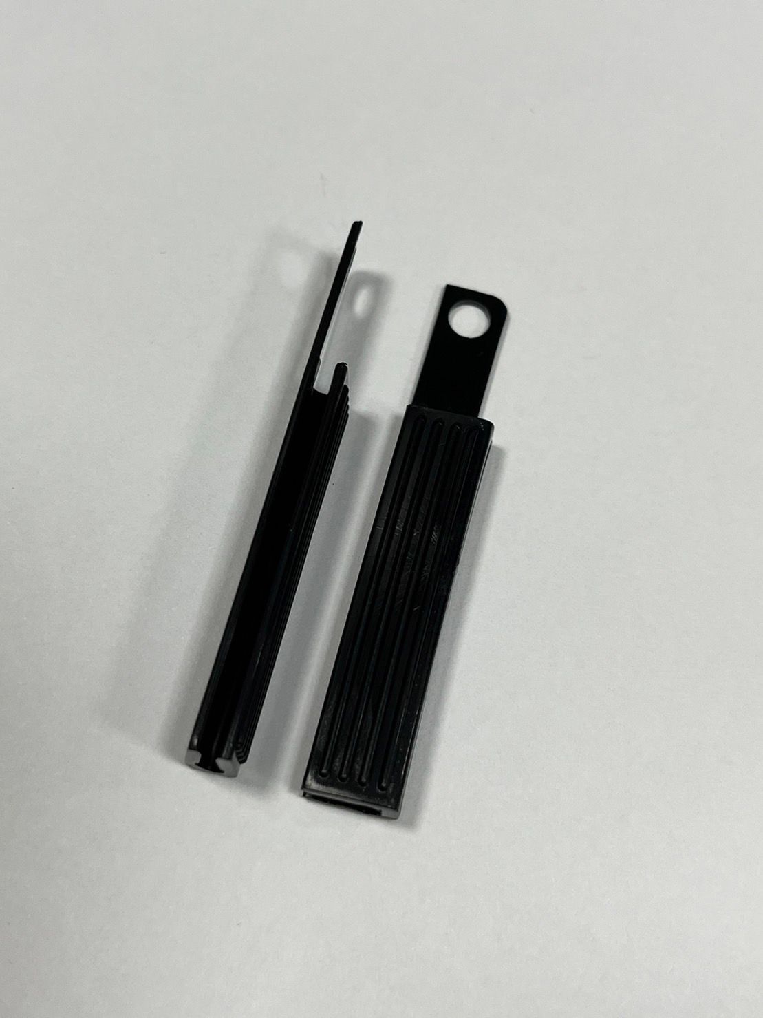 Two black objects are sitting on a white surface.