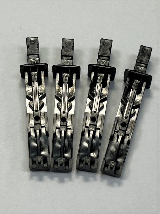 Four pieces of metal are sitting on top of each other on a white surface.