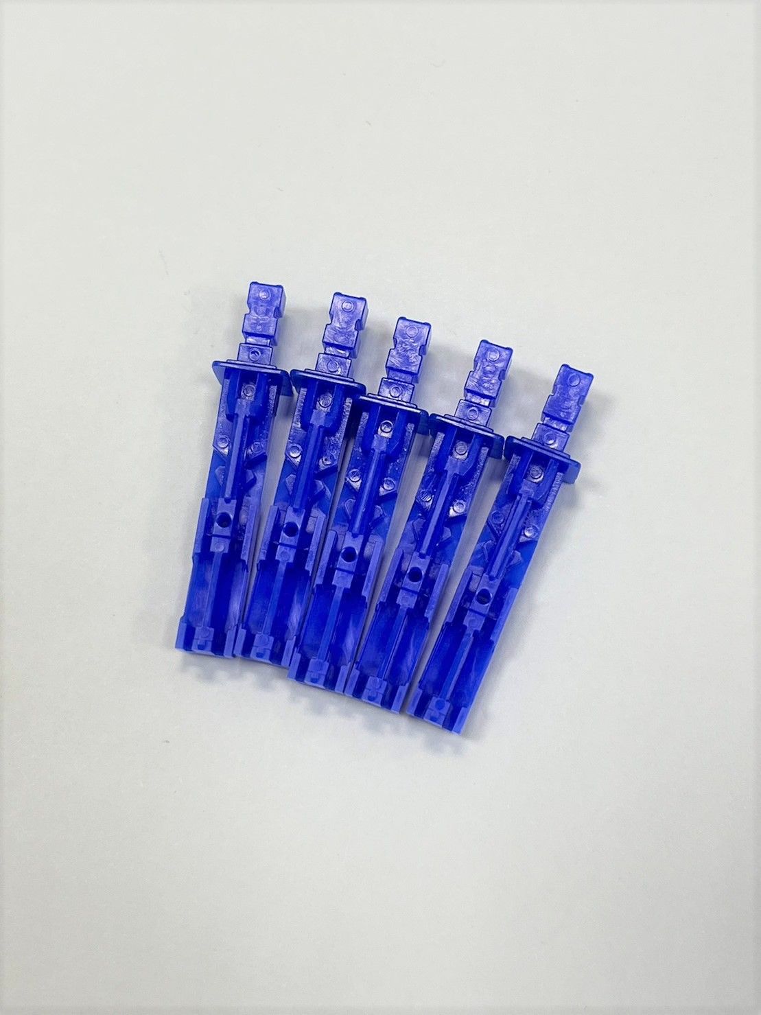 A bunch of blue clothes pins are sitting on top of each other on a white surface.