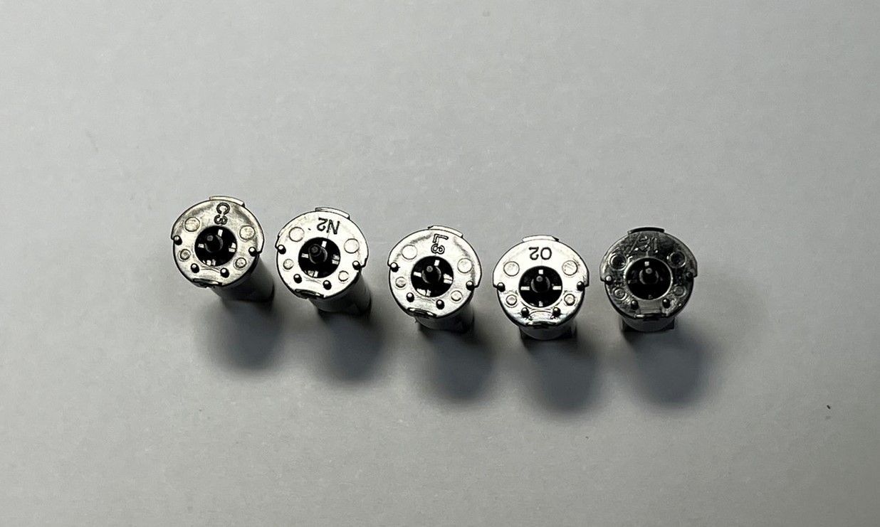 A row of screws are lined up on a white surface