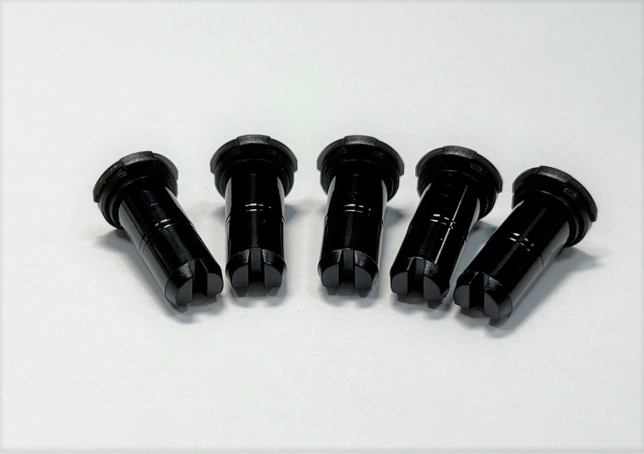A bunch of black screws are lined up in a row on a white surface