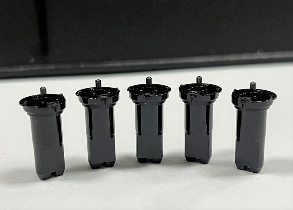 A row of black cylinders are lined up on a white surface