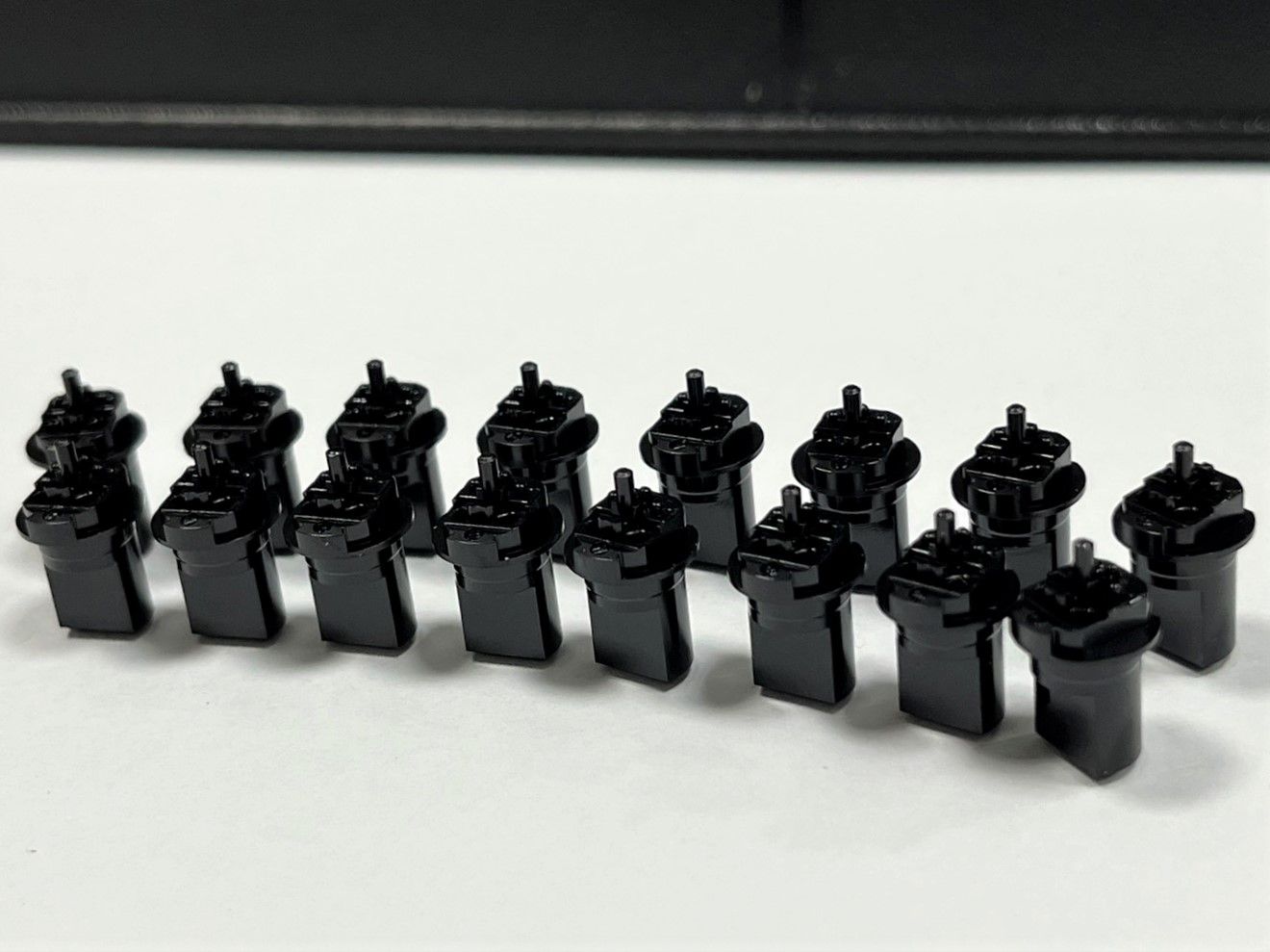 A row of black containers are lined up on a white surface.