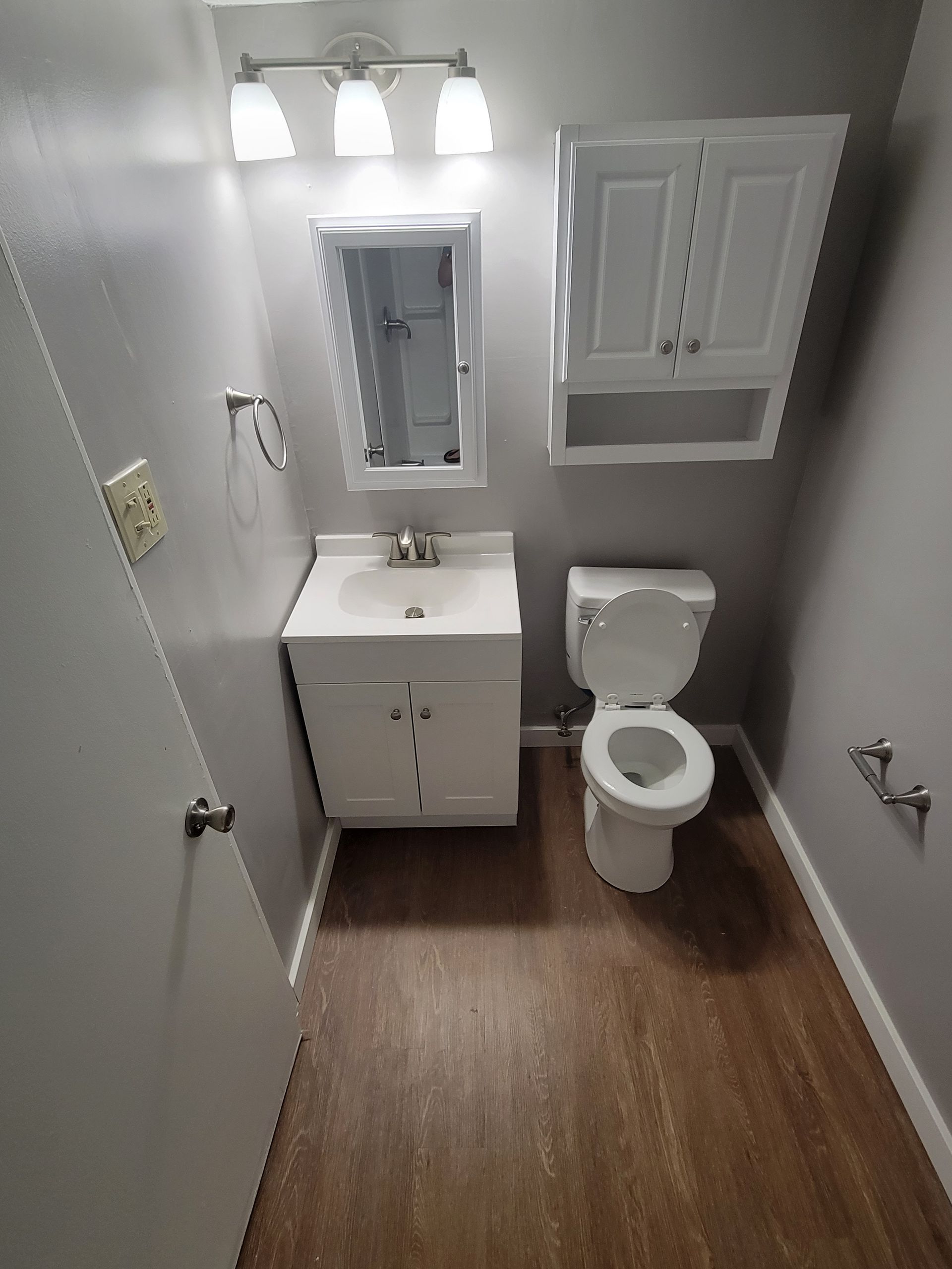 A bathroom with a toilet , sink and mirror.