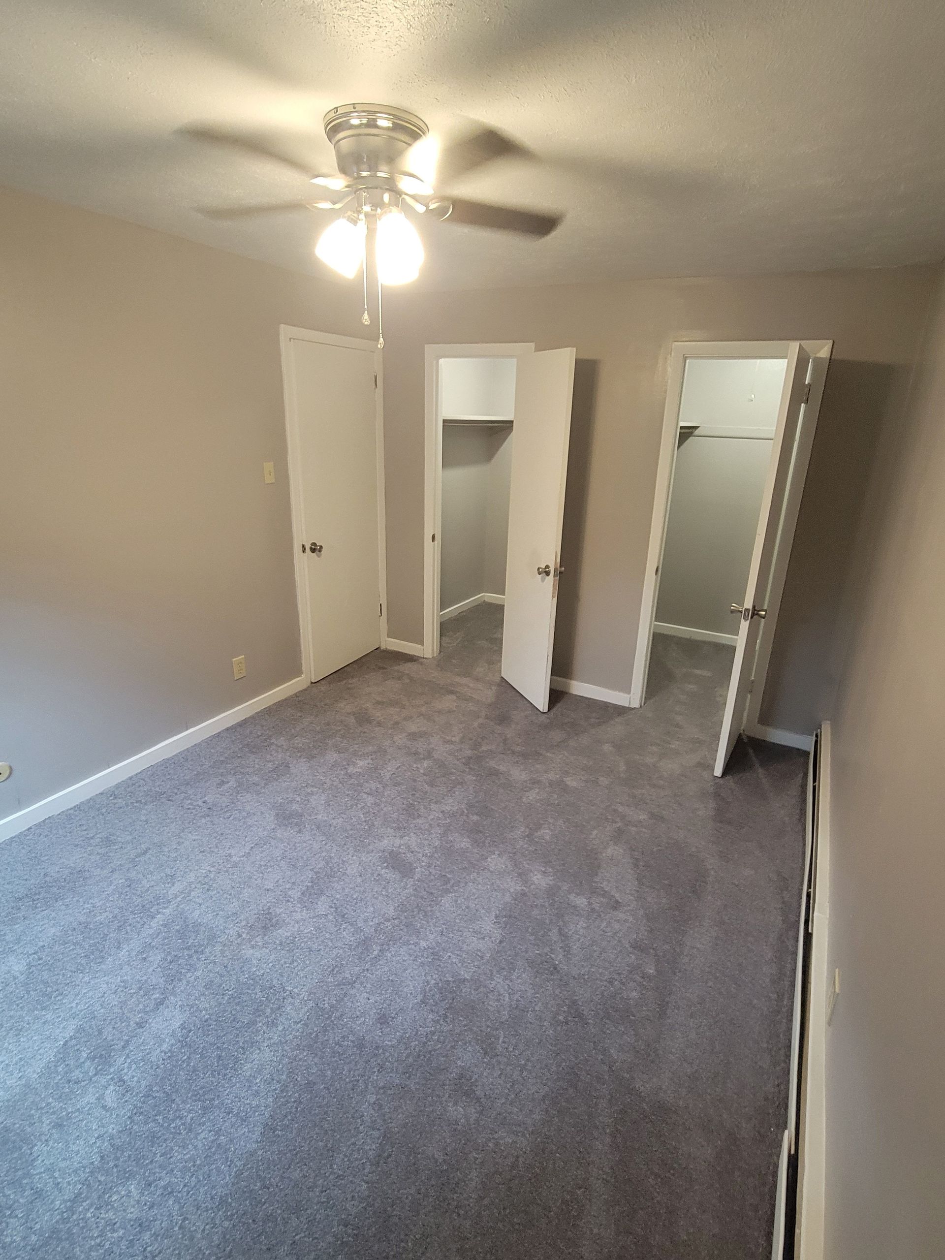 An empty bedroom with a ceiling fan and a walk in closet.