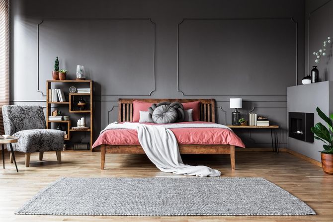 Bedroom with gray walls, wooden bed and furniture, pink bedding, and gray rug.