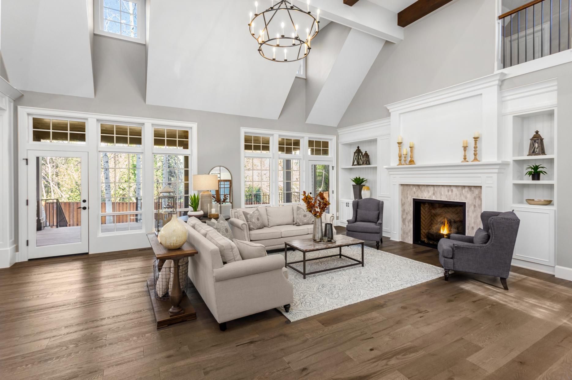 Spacious living room with fireplace, light-colored furniture, and large windows. 
