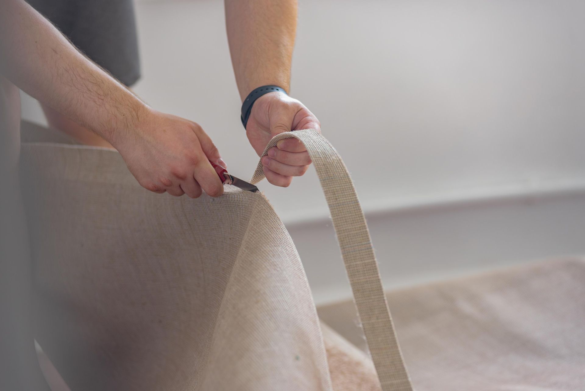 Person cutting a strip of carpet with a utility knife.
