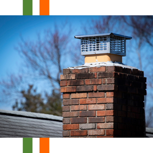A brick chimney on top of a roof with trees in the background.