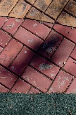 Brick paving with red and yellow bricks and a strip of green grass.
