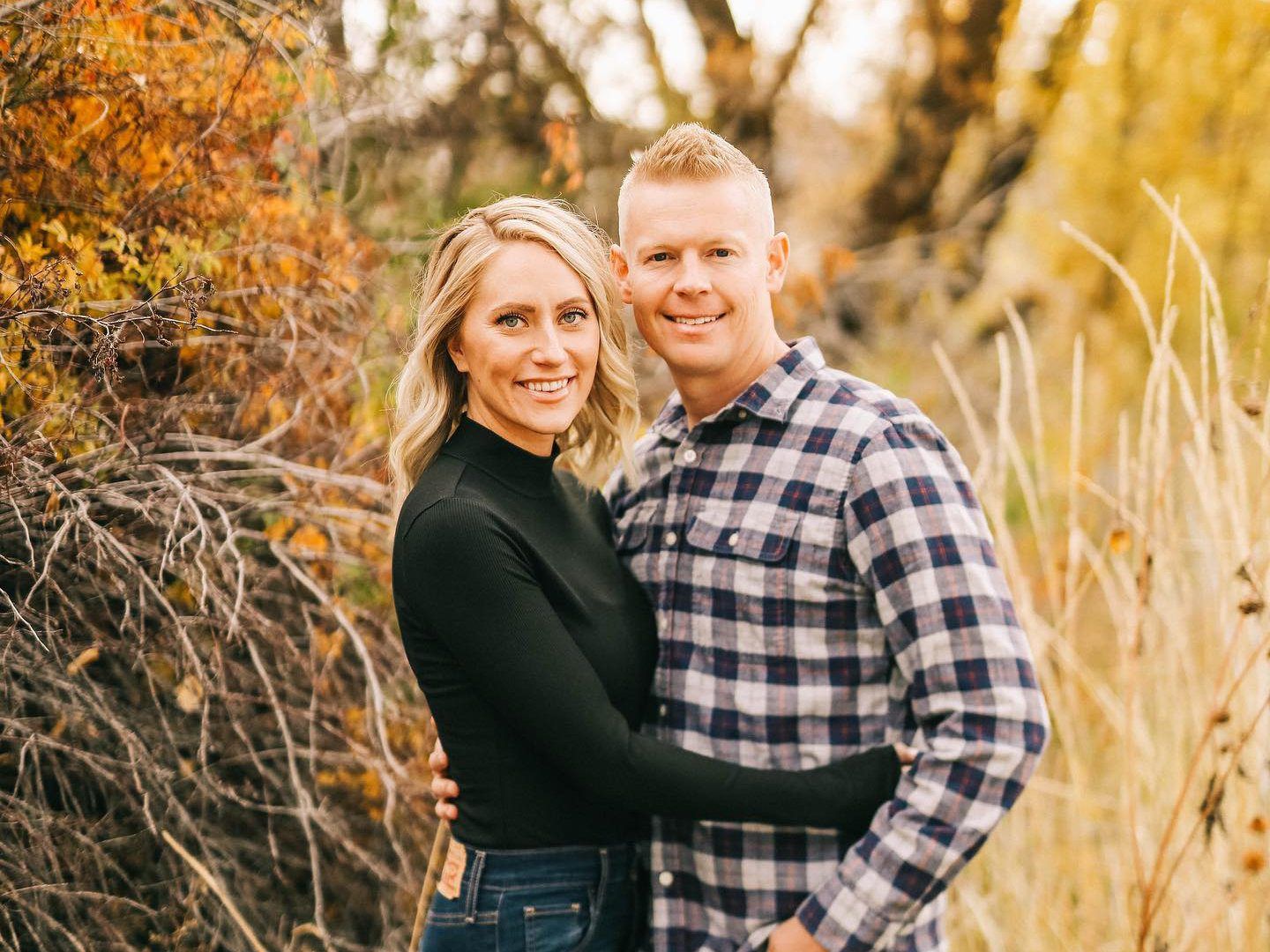 A man and a woman are posing for a picture in a field.