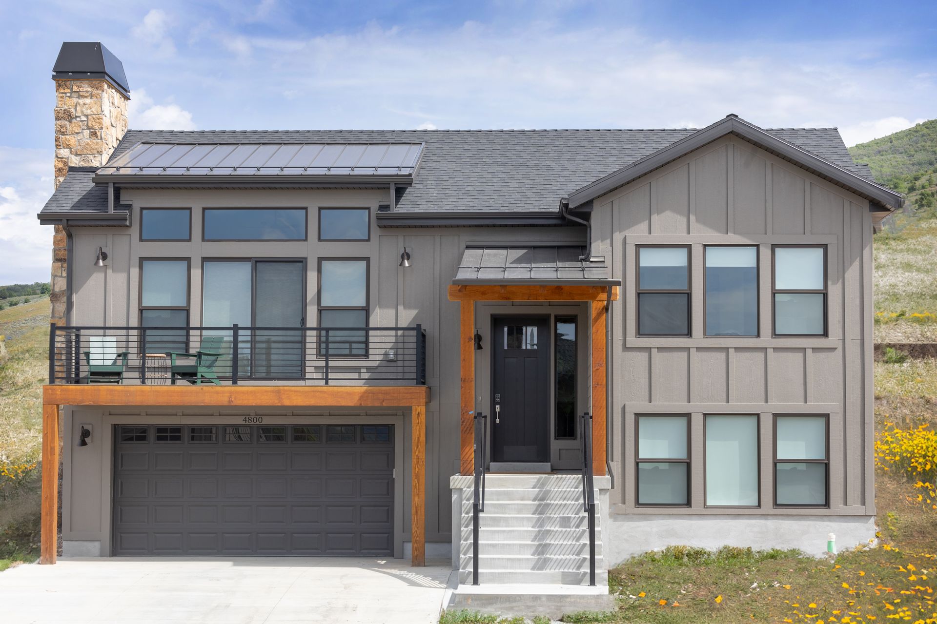 The home, Mountain Art Retreat, with balcony, 2 car garage, many windows, surrounded by mountains.