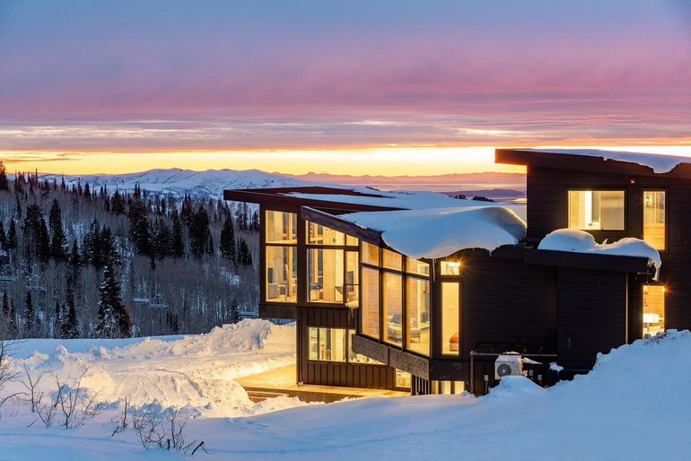 A large house is sitting on top of a snow covered hill.