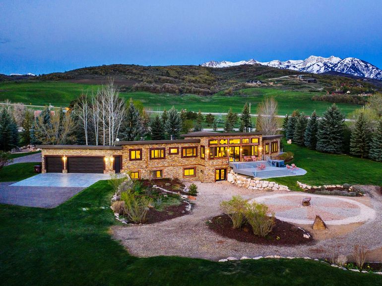 An aerial view of a large house with mountains in the background.