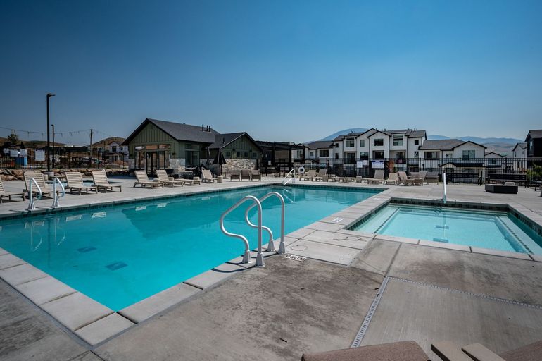 A large swimming pool surrounded by chairs and palm trees on a sunny day.